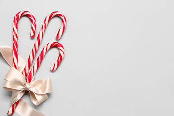 Sweet candy canes with ribbon on light background