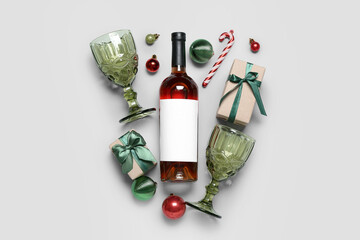 Bottle of wine with glasses, gifts and Christmas balls on light background