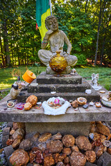 Geodes donated to small stone Tibetan Mongolian Buddhist statue in forest