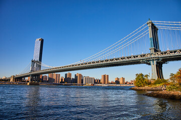 Fototapeta na wymiar View of entire Manhattan Bridge from Brooklyn in New York City over waters with blue sky