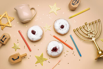 Menorah with donuts, dreidels and stars for Hannukah celebration on beige background