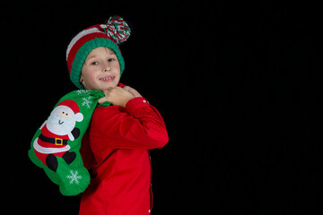 Little boy with a Christmas present on a black background.