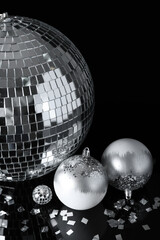 Disco ball with Christmas decor and confetti on black background