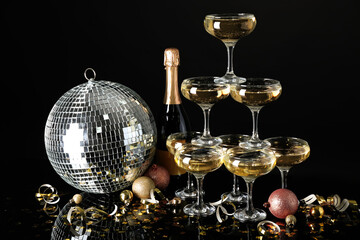 Obraz premium Glasses of champagne, bottle, Christmas balls and serpentine on black background
