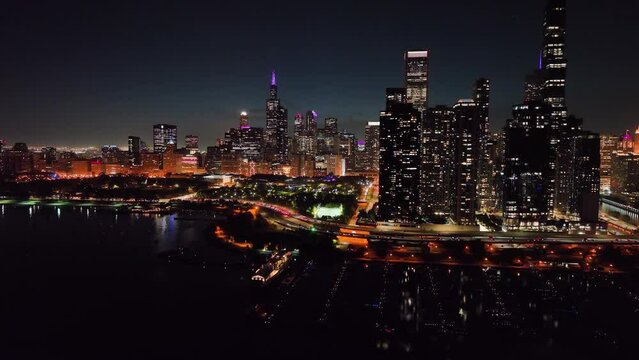 Flying over the DuSable Harbor, towards the Millennium Park, in Illuminated Chicago, USA - Aerial view