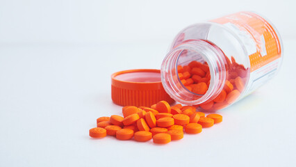 orange pills spilled out of a can on a white table, background image
