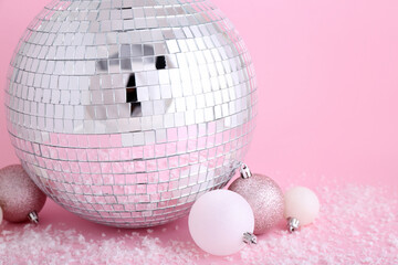 Disco ball with Christmas toys and snow on pink background