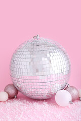 Disco ball with Christmas toys and snow on pink background