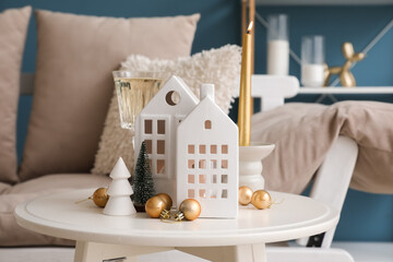Candle holders, Christmas trees, balls and glass of champagne on table in living room, closeup