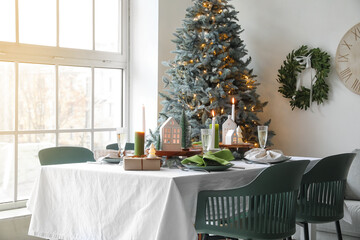 Christmas table setting with candle holders, presents and fir trees in dining room
