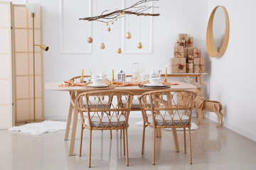 Interior of light room with dining table, tree branches and Christmas balls