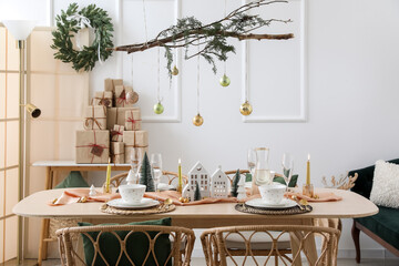 Interior of light room with dining table, tree branches and Christmas balls