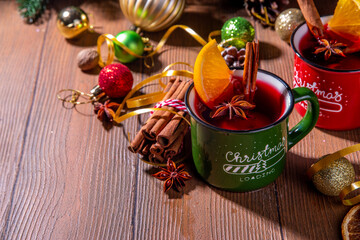 Christmas winter mulled wine drink. Classic style mulled red wine cocktail with orange slice, cinnamon, spices, on festive Christmas, New Year Noel decorated wooden background copy space