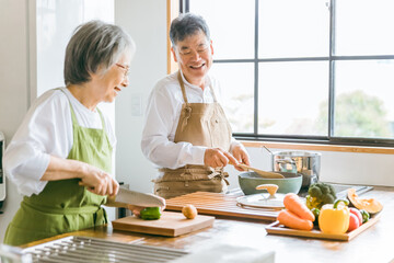 家のキッチンで一緒に料理・家事を楽しむ高齢者夫婦・シニアカップル  © buritora