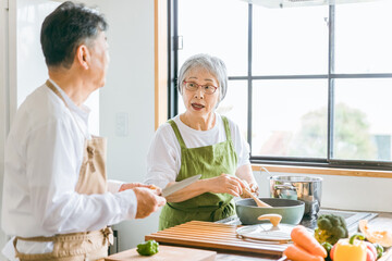 Fototapeta na wymiar 高齢者男性の料理に心配して教えるアジア人高齢者女性（困る） 