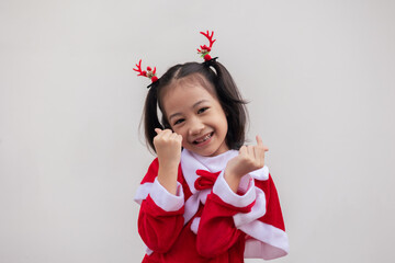 Portrait shot of adorable asian kid girl with red sweater for Christmas costume on white background shows concept of happiness celebration. It is the emotional face expression of enjoyment.