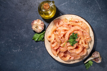 Cooking diet white poultry meat background. Fresh sliced chicken strips raw for cooking, with spices, herbs, on a black concrete background top view copy space