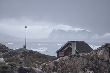 Casas de madera de colores en pueblo costero con icebergs flotando de fondo.