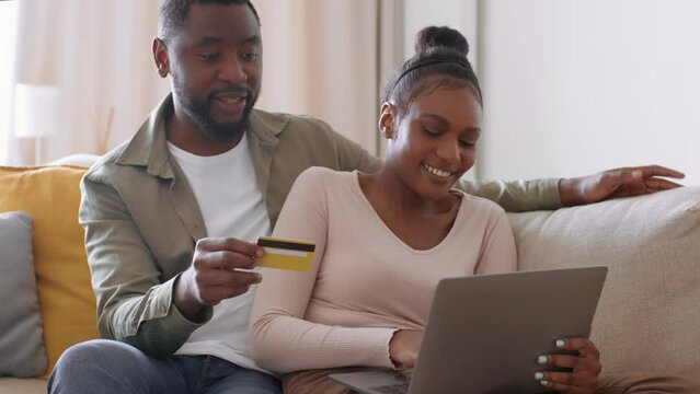 Online shopping. Happy african american man and woman doing purchases together at home, tracking shot, empty space