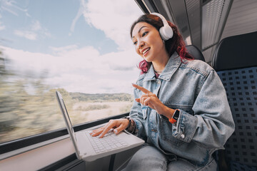 Girl streamer or video blogger, having online remote meeting or teaching and learning language via wi-fi Internet on her laptop screen while traveling on a train