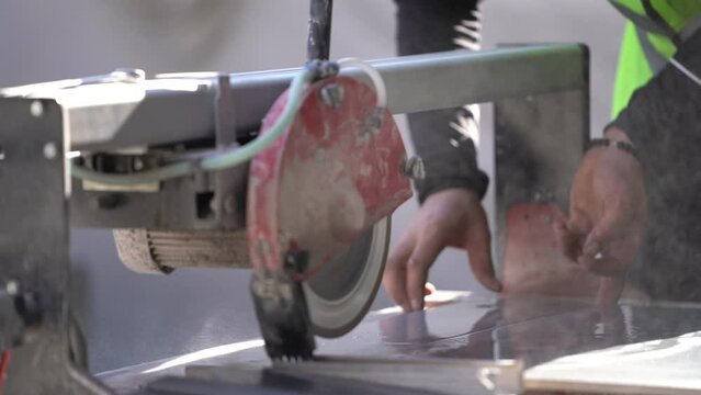 Cutting tiles with electric tile cutter with water. The master cuts the tile with an electric tile cutter.