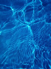 Bluewater waves on the surface ripples blurred. Defocus blurred transparent blue colored clear calm water surface texture with splash and bubbles. Water waves with shining pattern texture background.