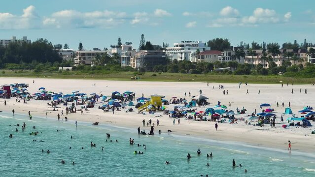 High angle view of crowded Siesta Key beach in Sarasota, USA. Many people enjoing vacations time swimming in ocean water and relaxing on warm Florida sun
