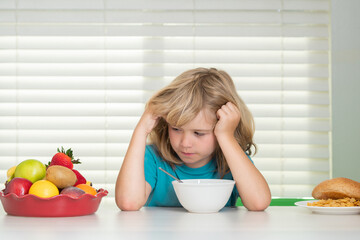 Portrait of kid with no appetite. Concept of loss of appetite. Portrait of preteen child eat fresh healthy food in kitchen at home. Kid boy eating breakfast before school.