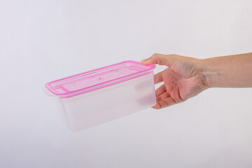 Pink plastic food container in hand isolated on white background.