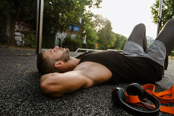 Tired sportsman resting after workout while lying on a ground on sports court