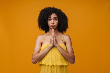 Young african american woman doing pray gesture with folded hands and looking up isolated