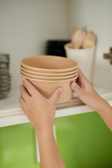 Woman Putting Disposable Bowls on Shelf