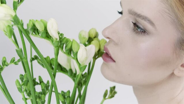 Face of young woman with clean smooth skin and small branch in hands. Natural and organic cosmetics, skin care, shampoo. Natural make-up. Woman with exotics frowers. Opens eyes. 