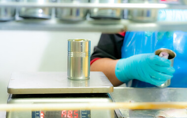 Sardines cans weigh on a weight scale by worker. Worker working in canned food factory. Food...