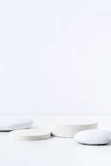 A minimalistic scene of white gypsum podium with stones on white background, for natural cosmetics
