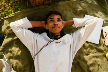 Relaxed african man lying on his back on blanket in park