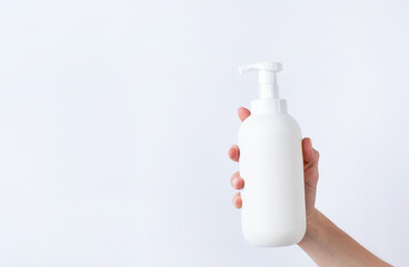 Woman hand holding blank white plastic container in light gray background