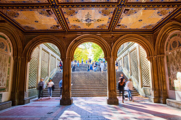 People walking through Central Park stairs and limestone arches with murals on ceiling in New York City