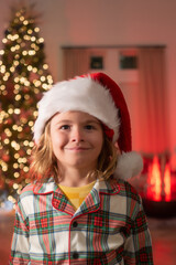 Kid in Christmas pajama enjoying winter holiday evening at home near the night Christmas tree.