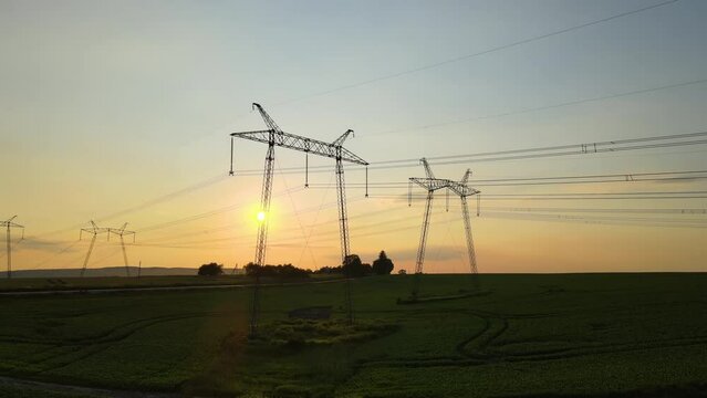 High voltage towers with electric power lines at sunset