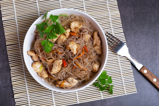 Green funchosa vermicelli dish with chicken on a bamboo mat