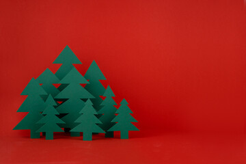 Christmas festive background in traditional red and green color with green paper spruces in minimal cartoon style, copy space. New year mockup for presentation, design, card, poster, flyer.