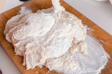 Process of kneading dough on wooden board sprinkled with flour for pizza. Home cooking 