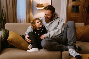 Father resting with his son on couch at home