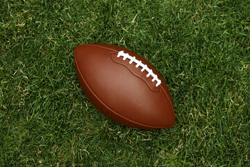 American football ball on green grass background