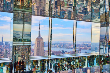 Stunning Empire State Building viewed high up in reflective mirror skyscraper with tourists