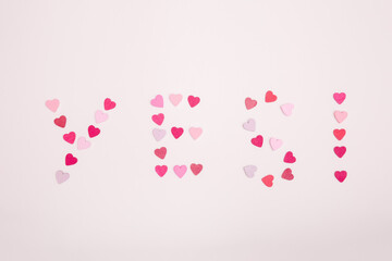 The word yes and an exclamation mark made from hearts on a gray background. The answer is yes to a marriage proposal.