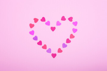 Heart-shaped frame made of small hearts on a pink background. The concept of Valentine's day, love, dating and wedding. Symbol of a romantic gift or marriage proposal. Copy space, minimalism.