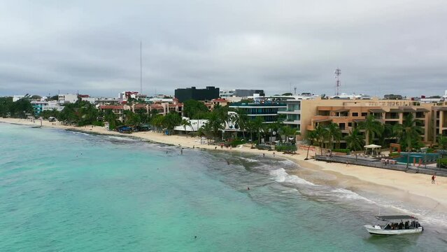 vibrant turquoise blue water in Playa Del Carmen with beachfront hotels on gloomy cloudy day, aerial