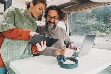 Modern couple of traveler enjoy work office inside camper van. Happy woman and man in modern job activity with freedom of motor home vehicle. Alternative vacation and lifestyle people. Travel rv
